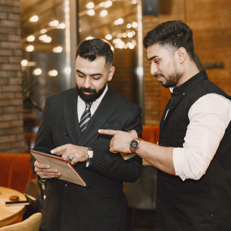 Handsome man in a black suit. Businessmen working in a cafe. People stands and looks in a documents.